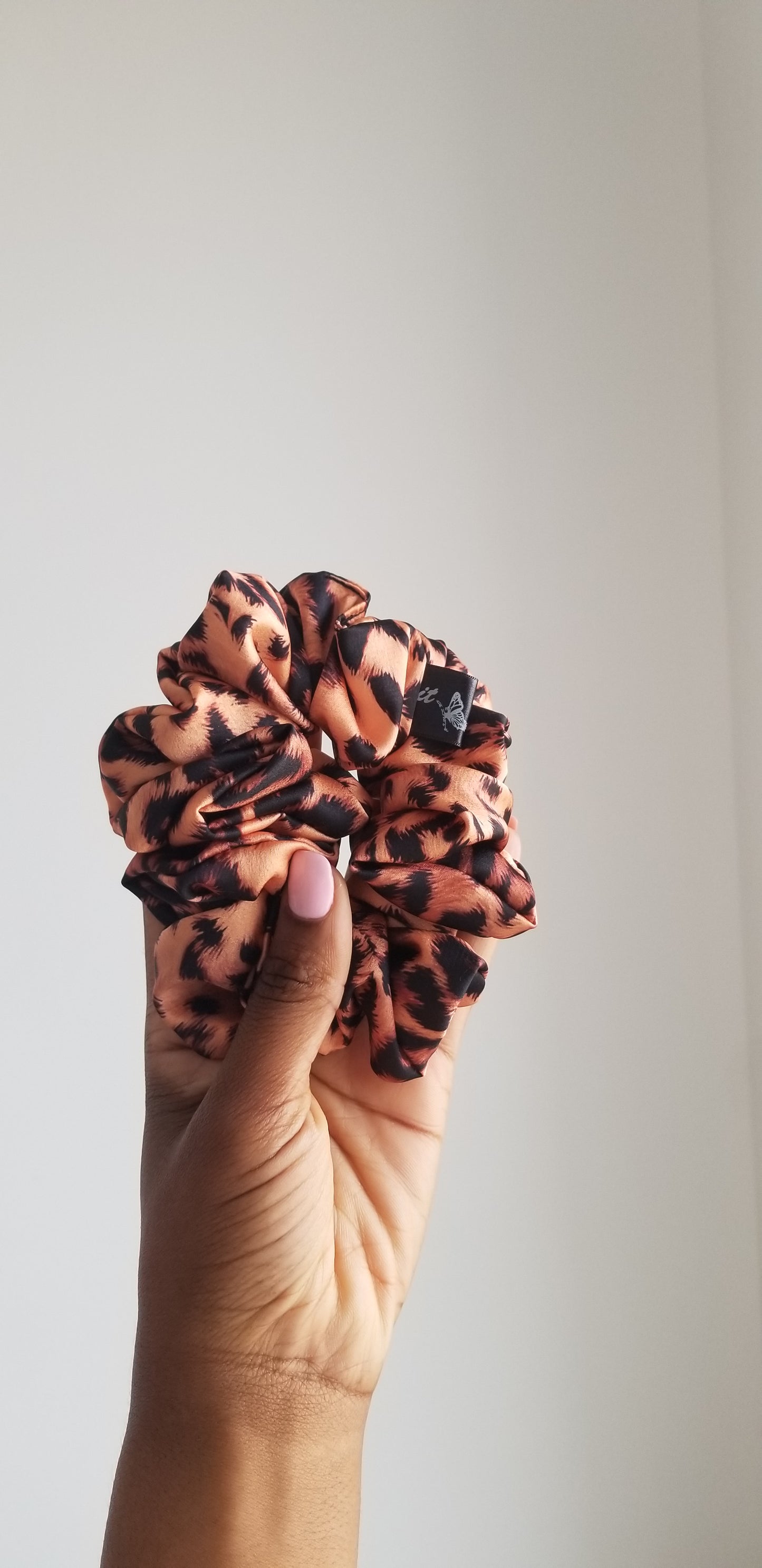 Front view of the Safari Cream light leopard print silk scrunchie by Scope and Flow on a marble surface.