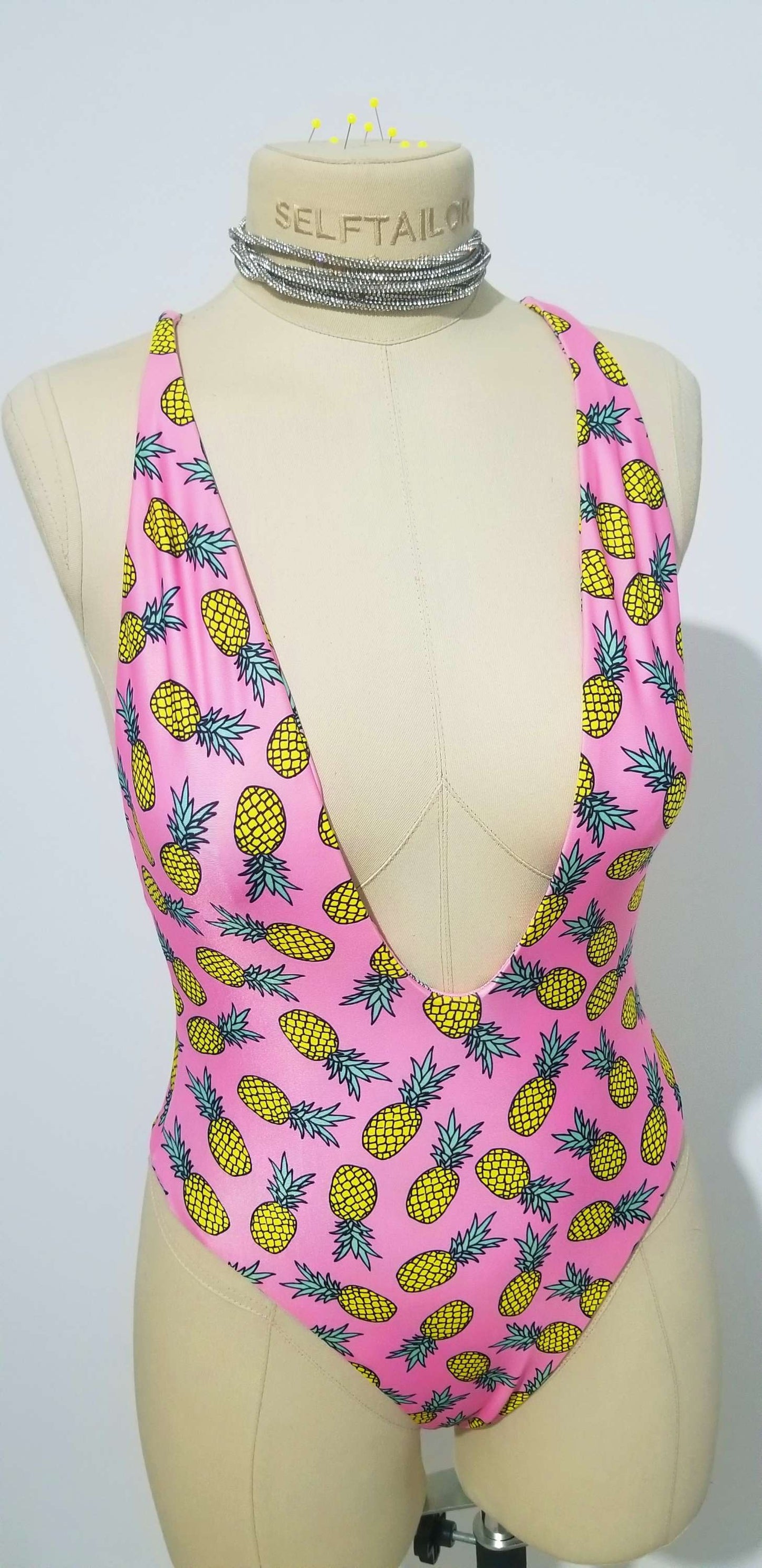 a female mannequin wearing a pink and yellow swimsuit with pineapples