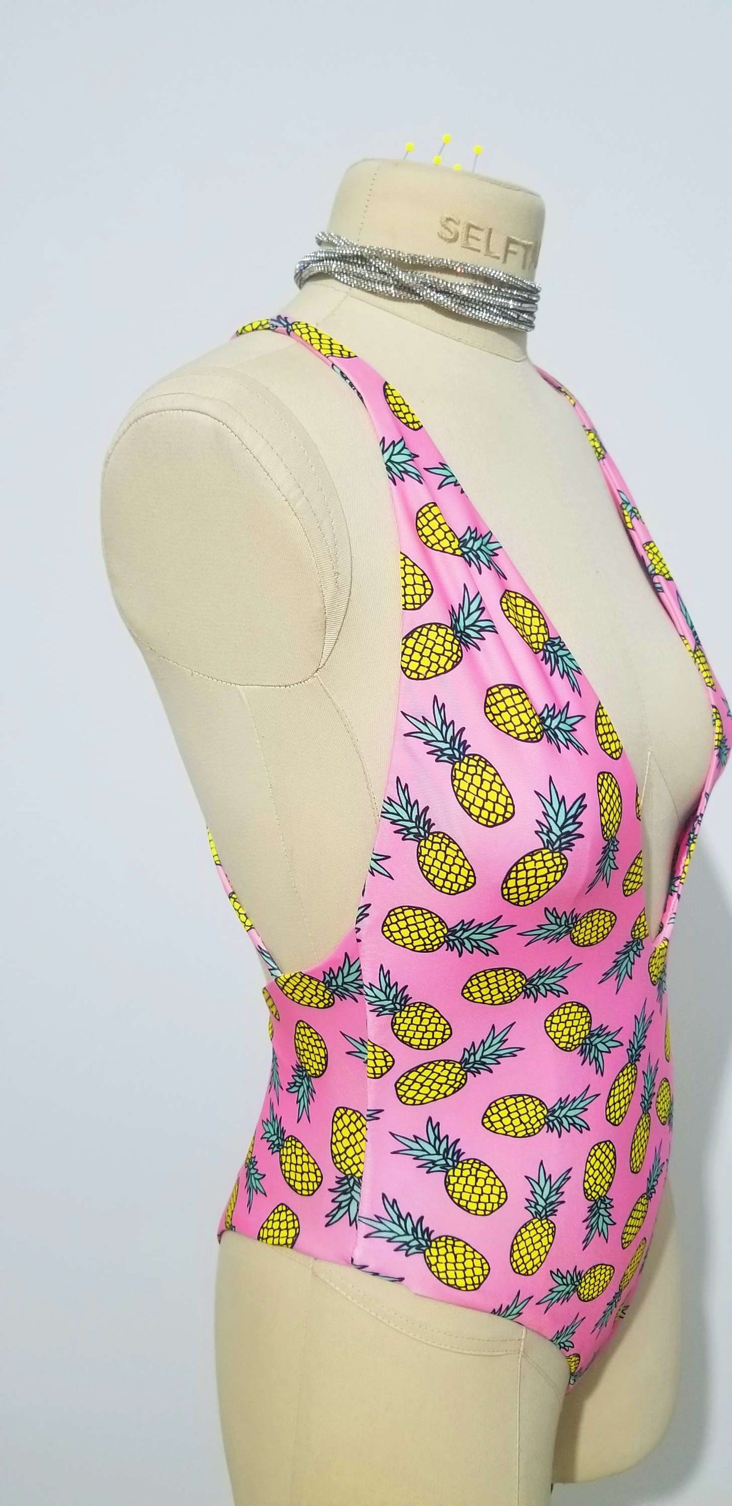 a female mannequin wearing a pink bikini top with pineapples on it