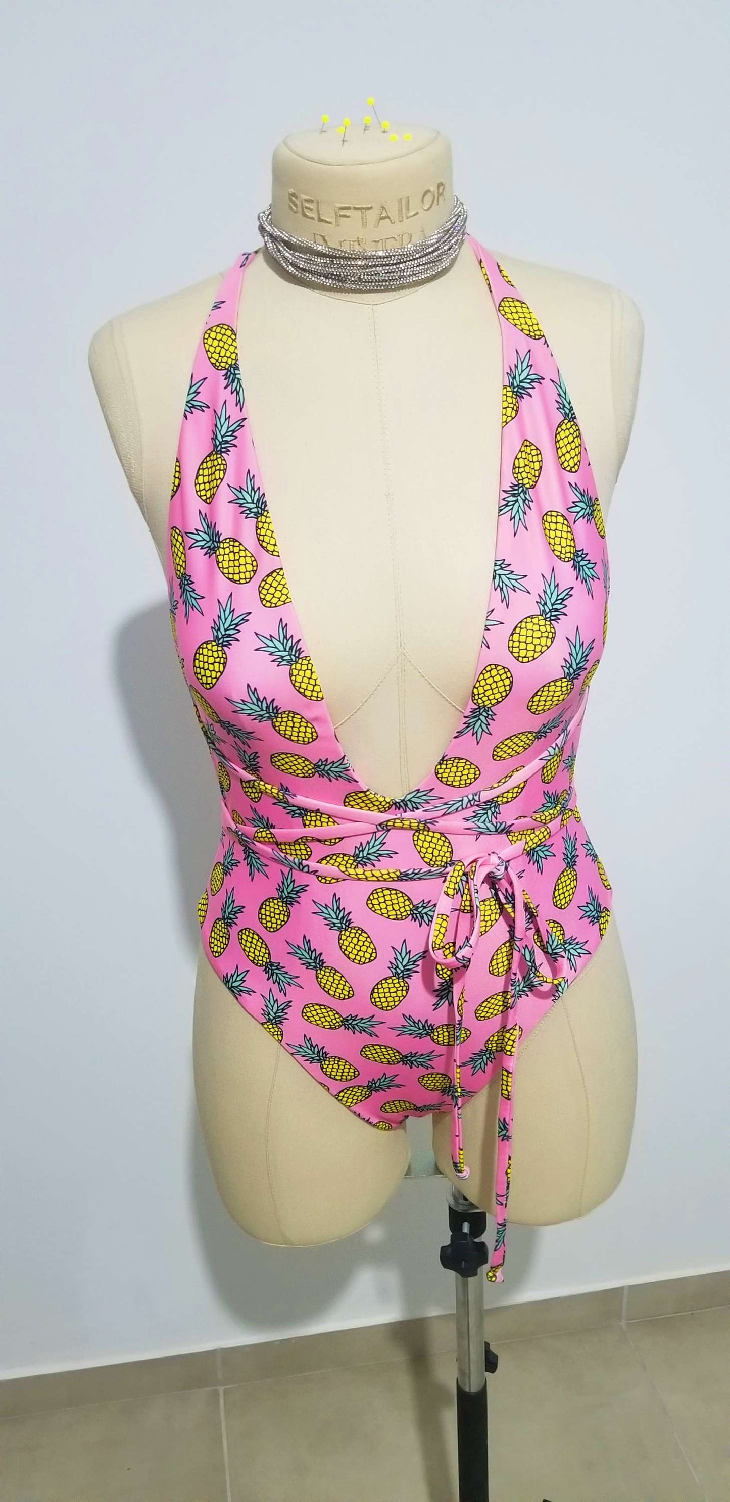 a mannequin wearing a pink bikini top with pineapples on it