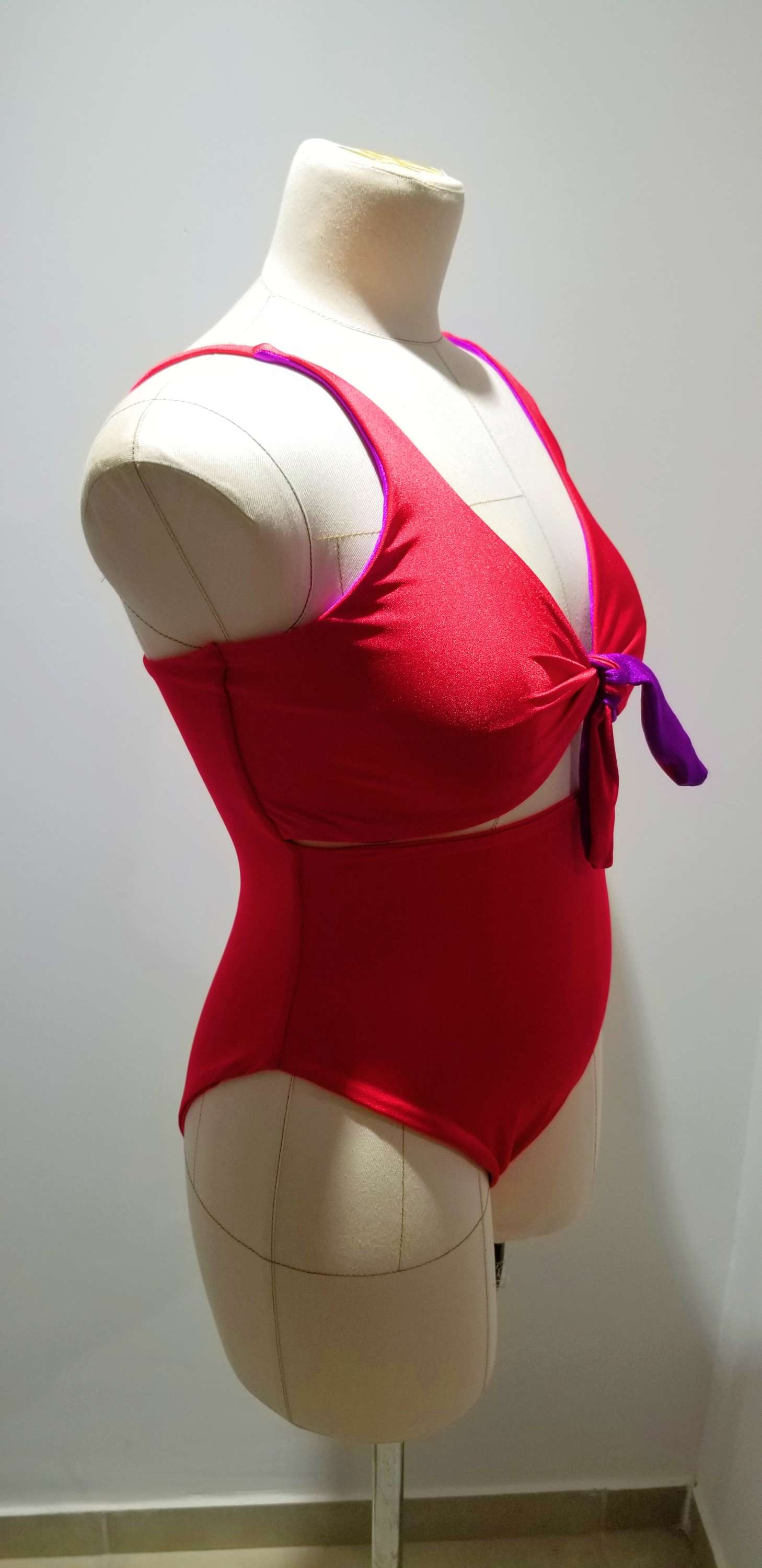 a mannequin wearing a red swimsuit with a purple ribbon