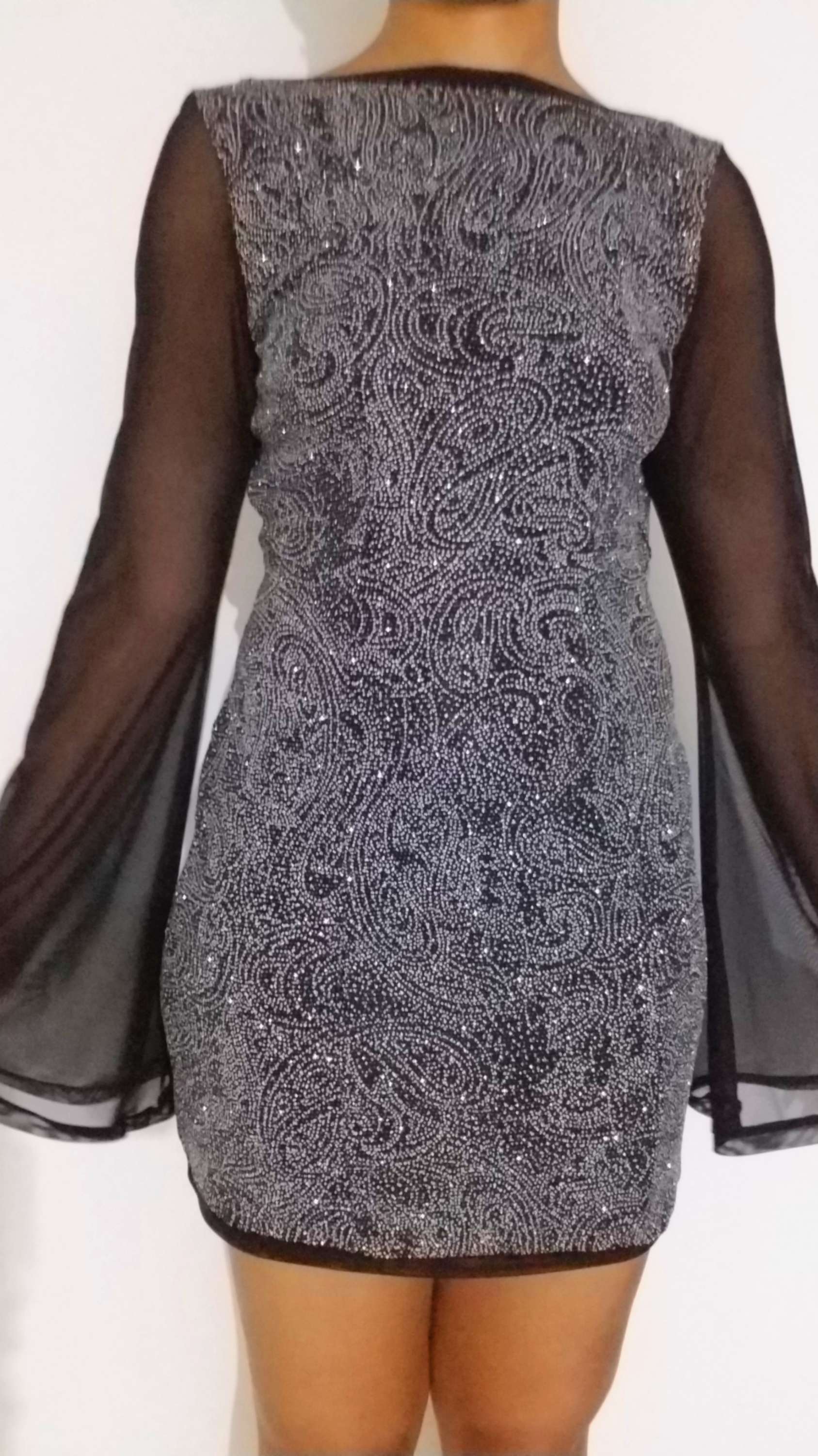 the back of a woman's dress with sheer sleeves