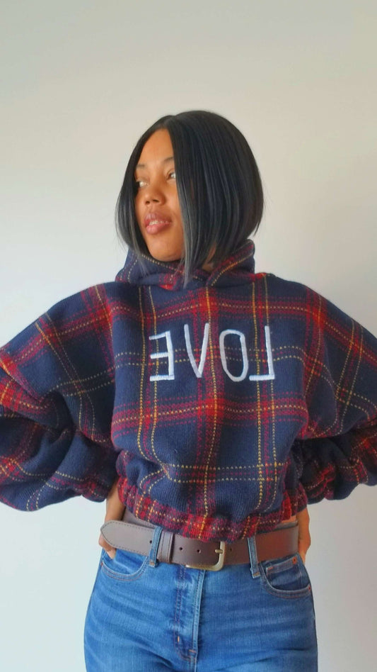 a woman wearing a plaid sweater with the word love on it