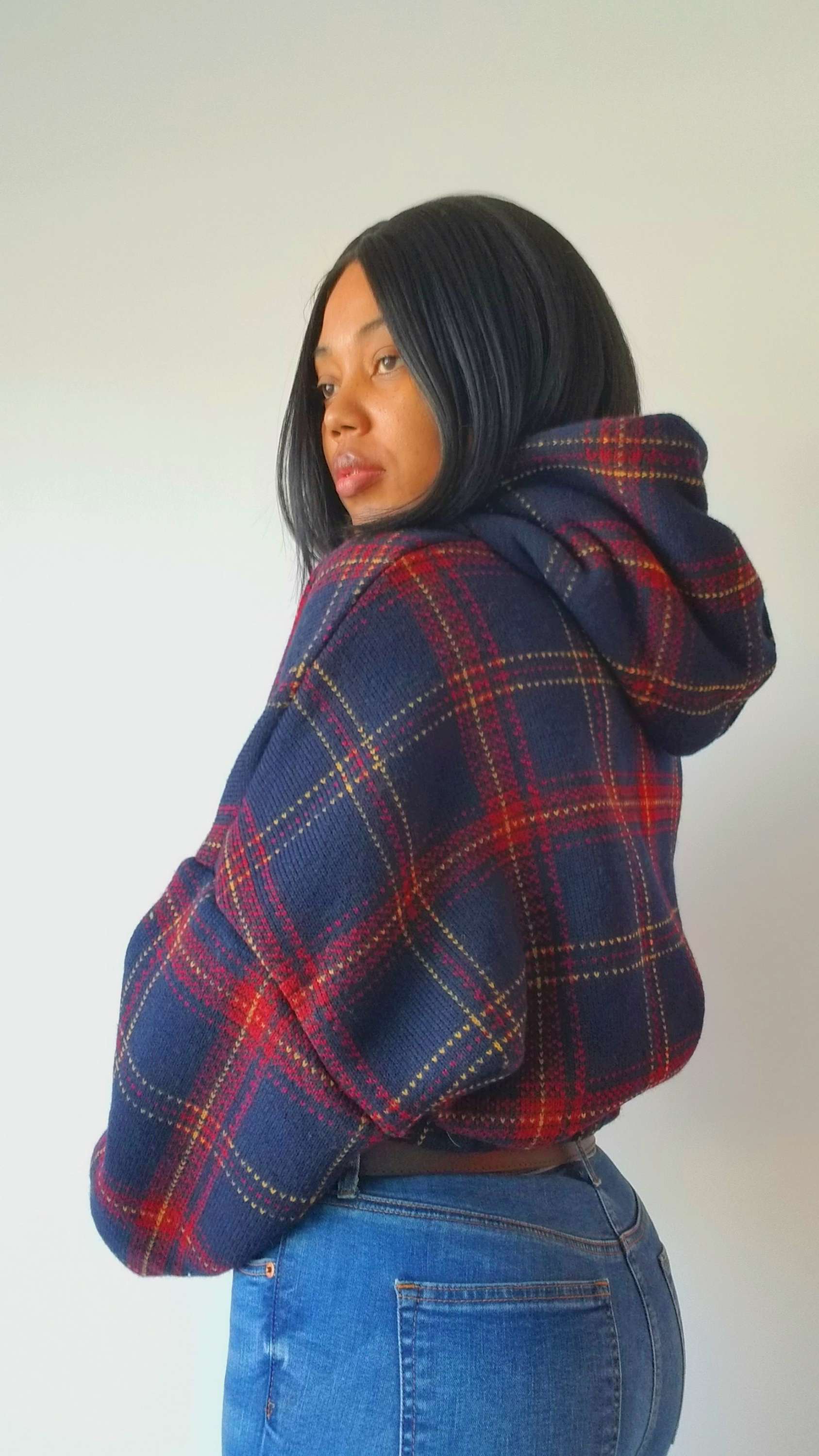 a woman wearing a plaid jacket and jeans