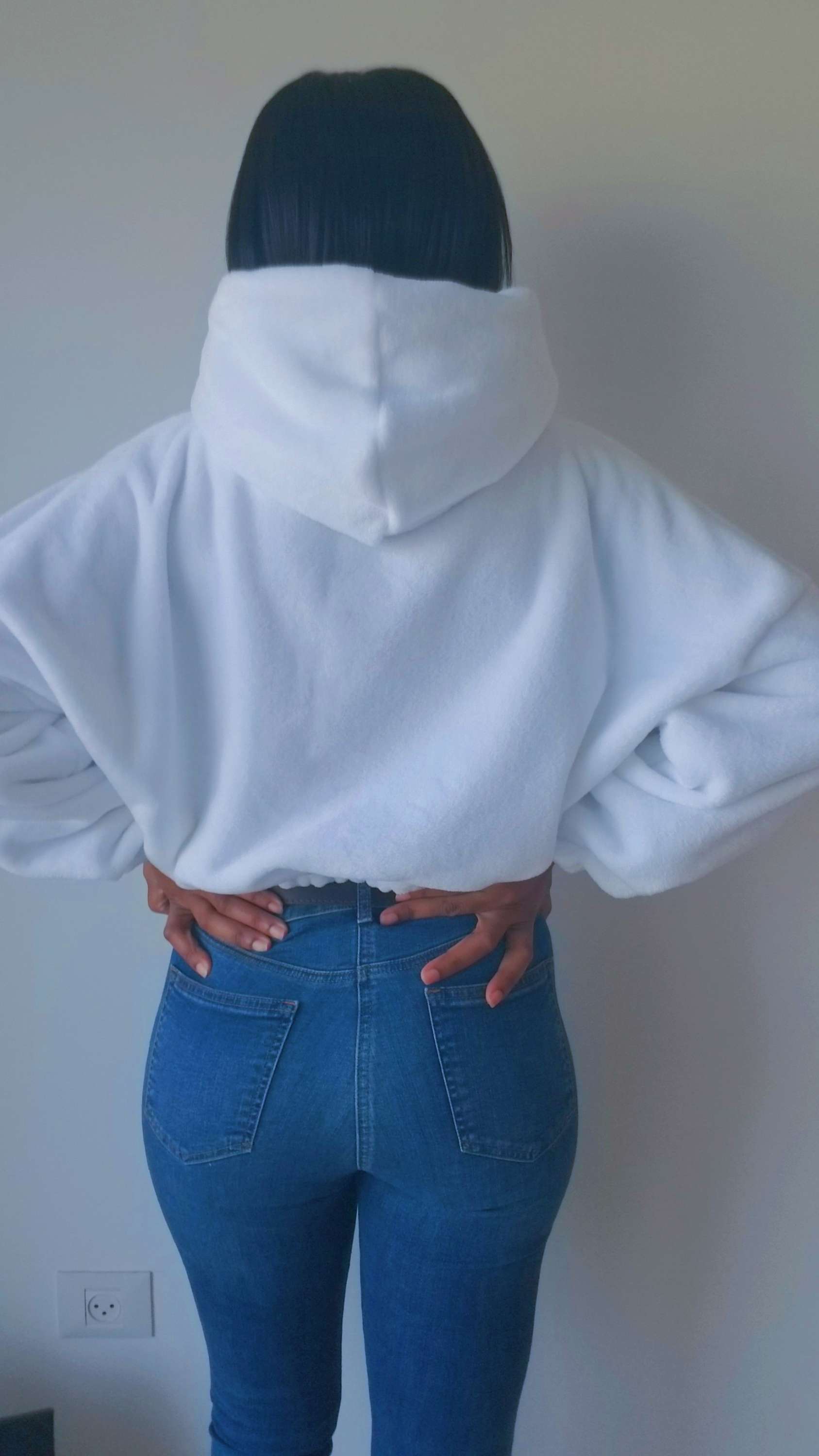 a woman wearing a white hoodie and jeans