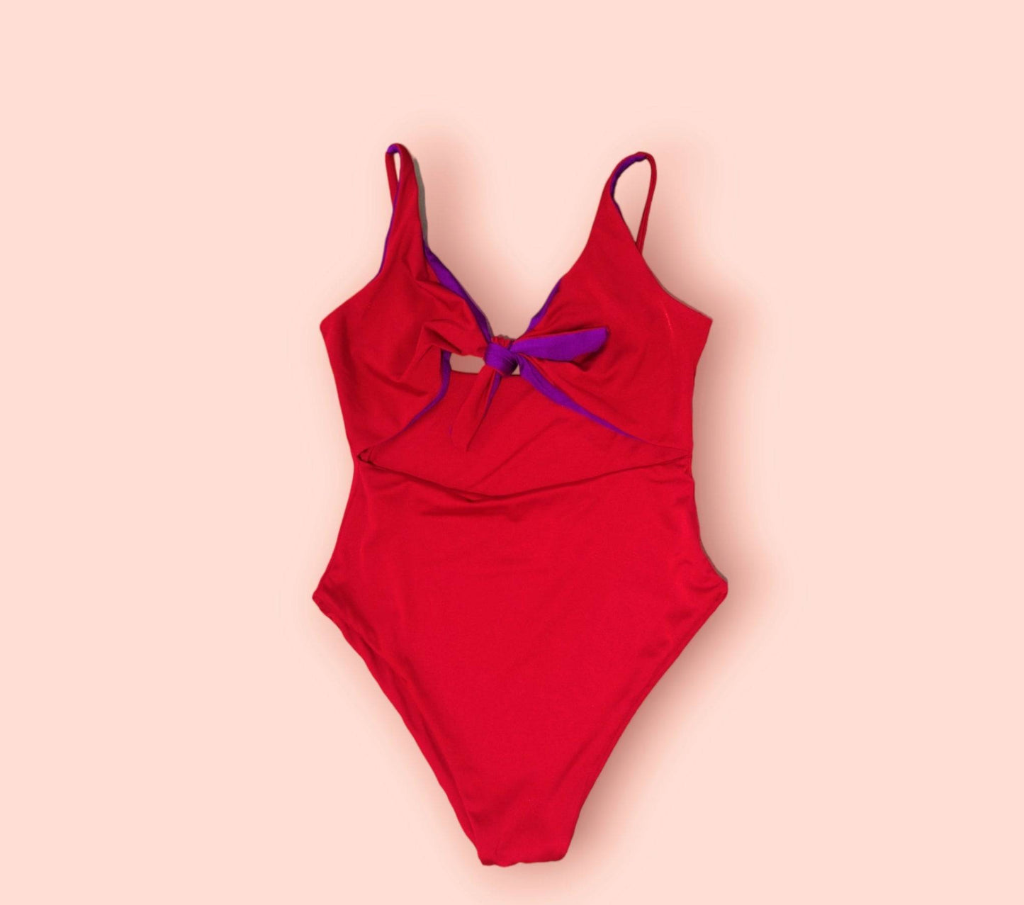 a red one piece swimsuit with a purple bow