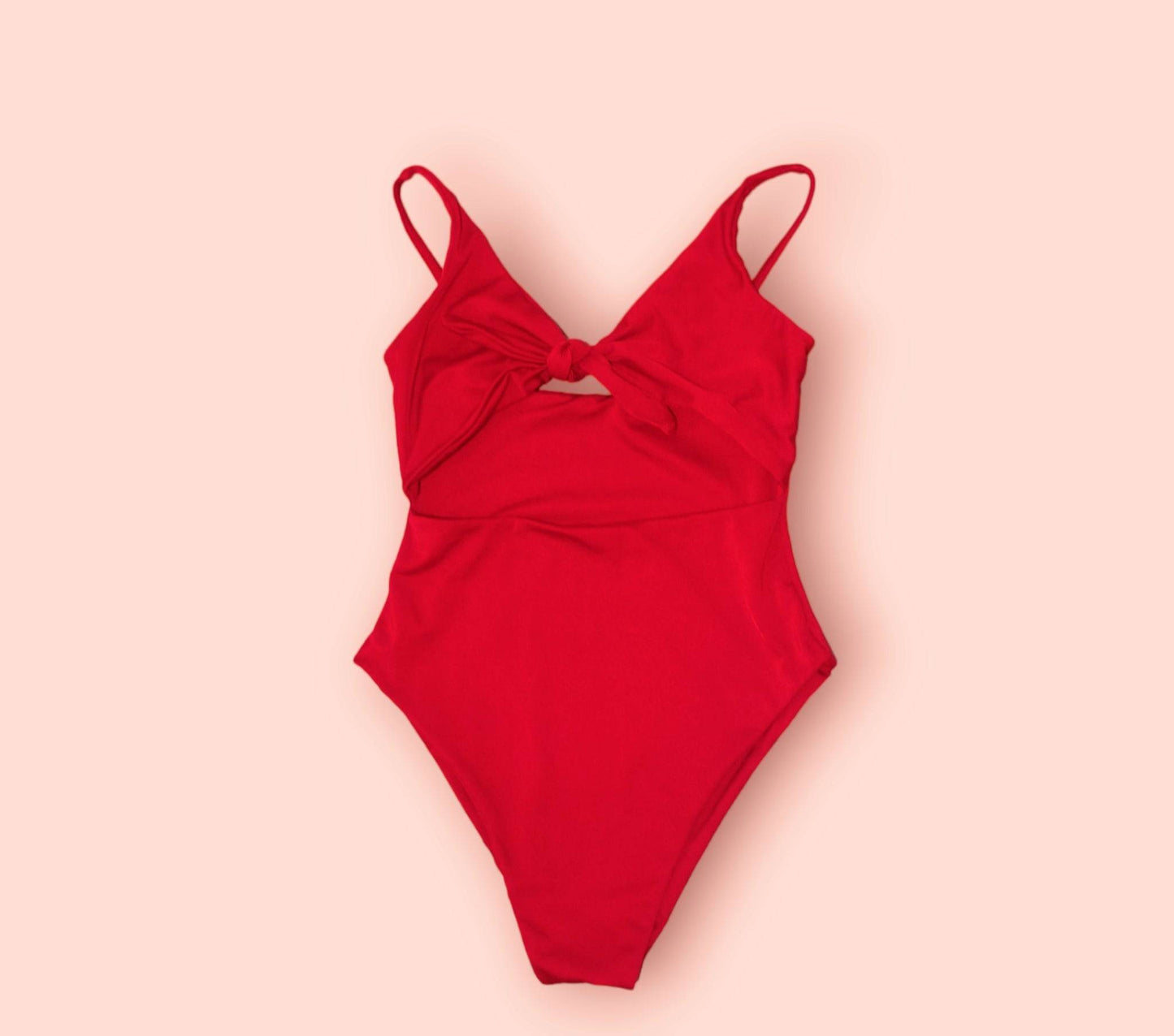 a red one piece swimsuit on a pink background