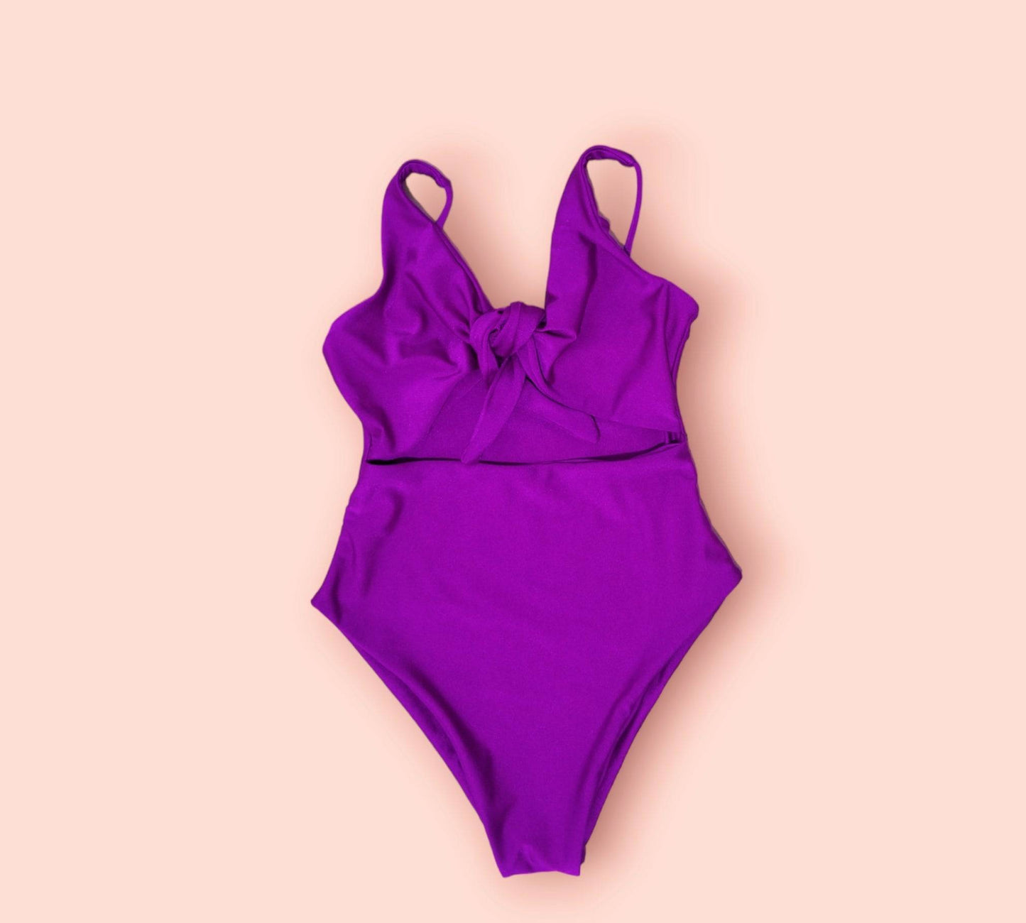 a purple one piece swimsuit on a pink background