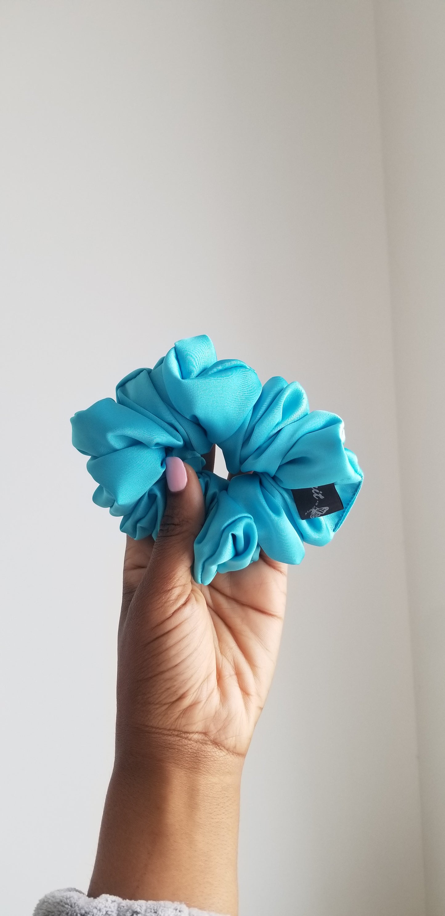 Front view of a handmade vibrant blue silk scrunchie by Scope and Flow, styled on a white marble surface.