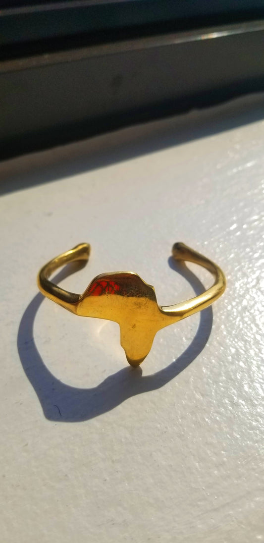 Top-down view of the 18K gold plated Continent Cuff featuring a hand-finished African map silhouette with artistic natural shadows.