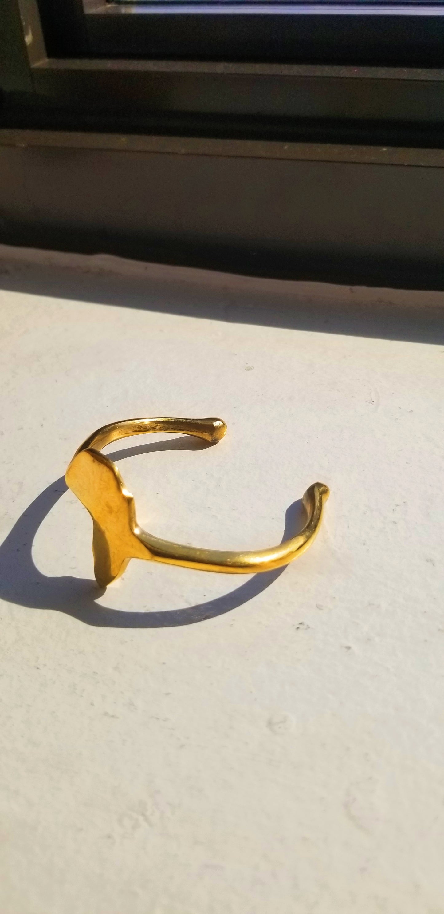 Side profile view of the gold Africa map bangle showcasing the thickness of the adjustable band and high-shine finish.
