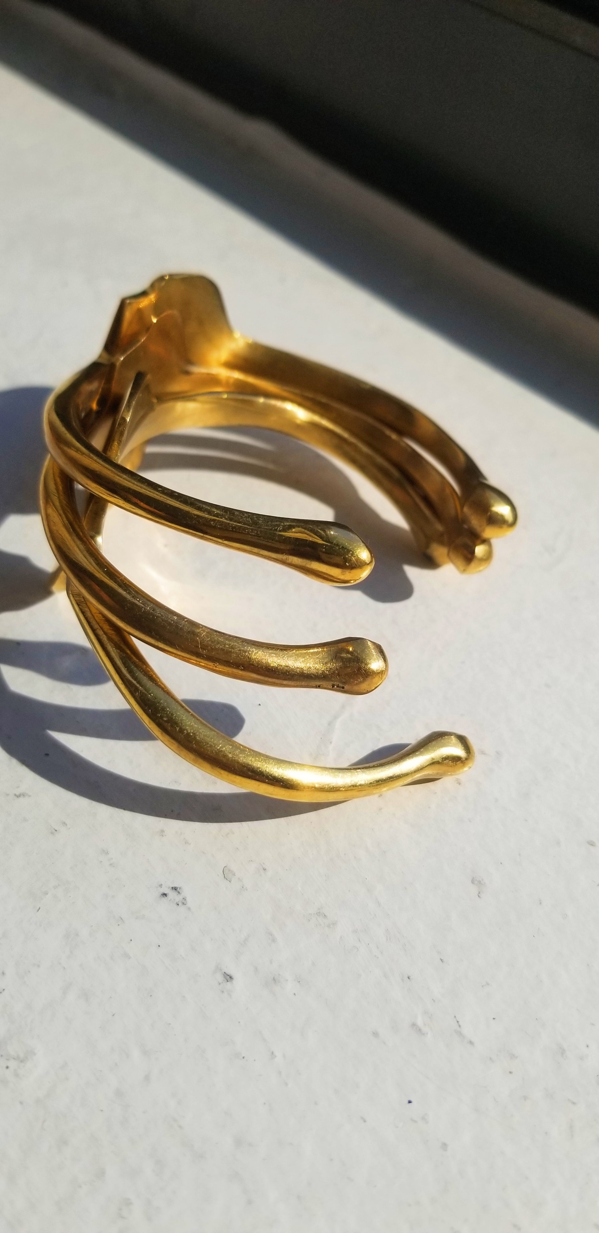 Close-up of gold Continent Cuffs showing the high-quality gold plating and architectural silhouette from an angled perspective.