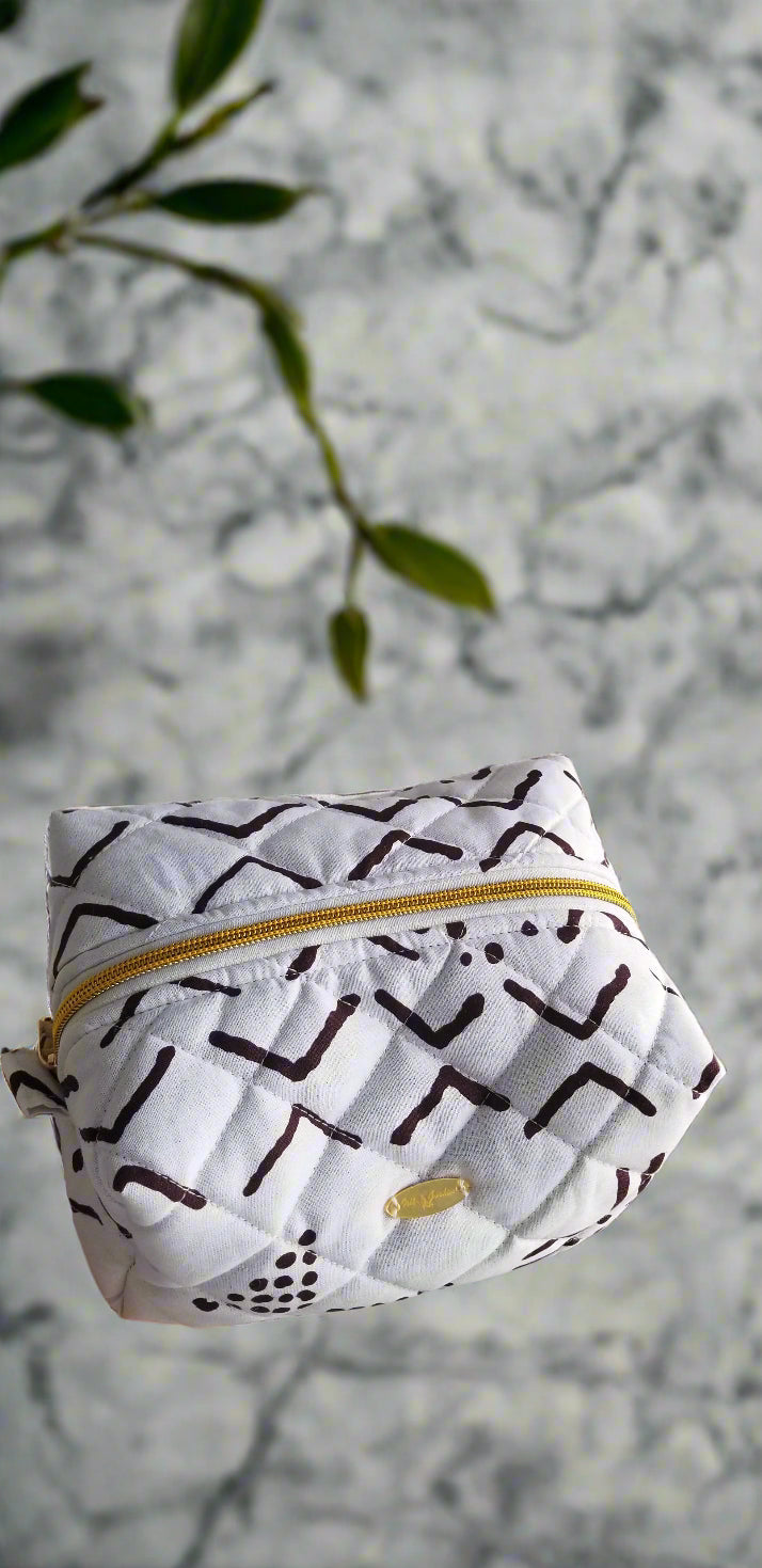 Side perspective of the handmade Ethereal Monochrome makeup bag styled with gold bathroom fixtures.