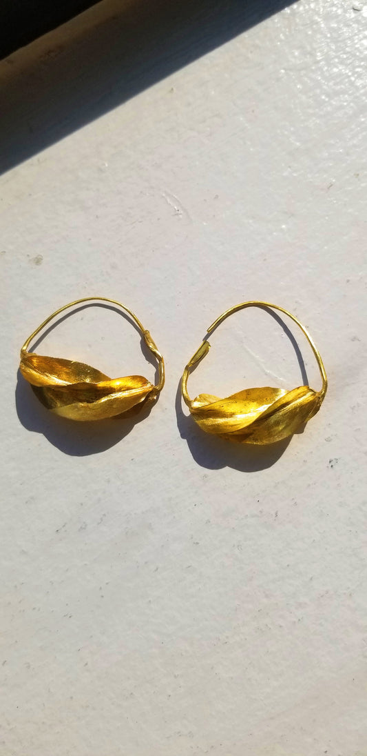 Pair of hand-twisted gold Fulani hoop earrings on a neutral background, highlighting the authentic African craftsmanship.