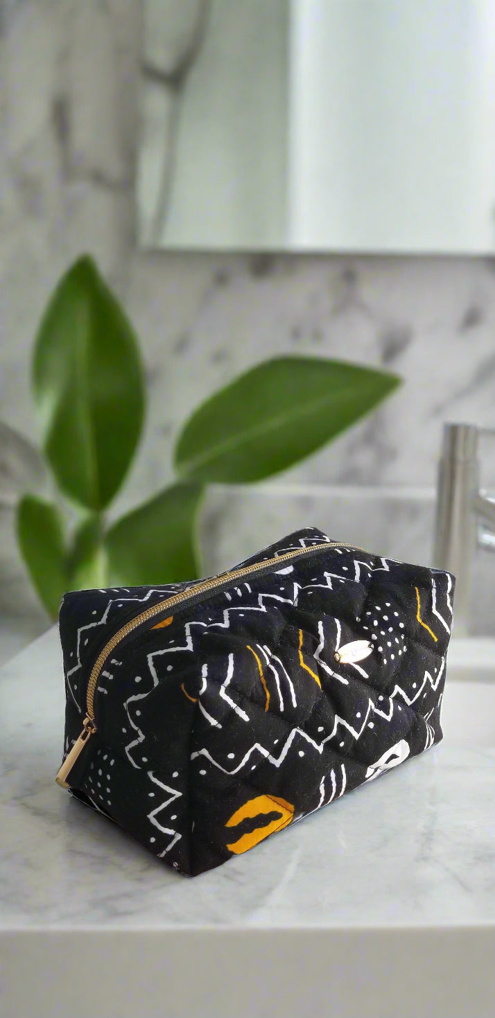 Top-down close-up of the Gold & Noir makeup bag, highlighting the intricate black, white, and gold geometric tribal patterns.
