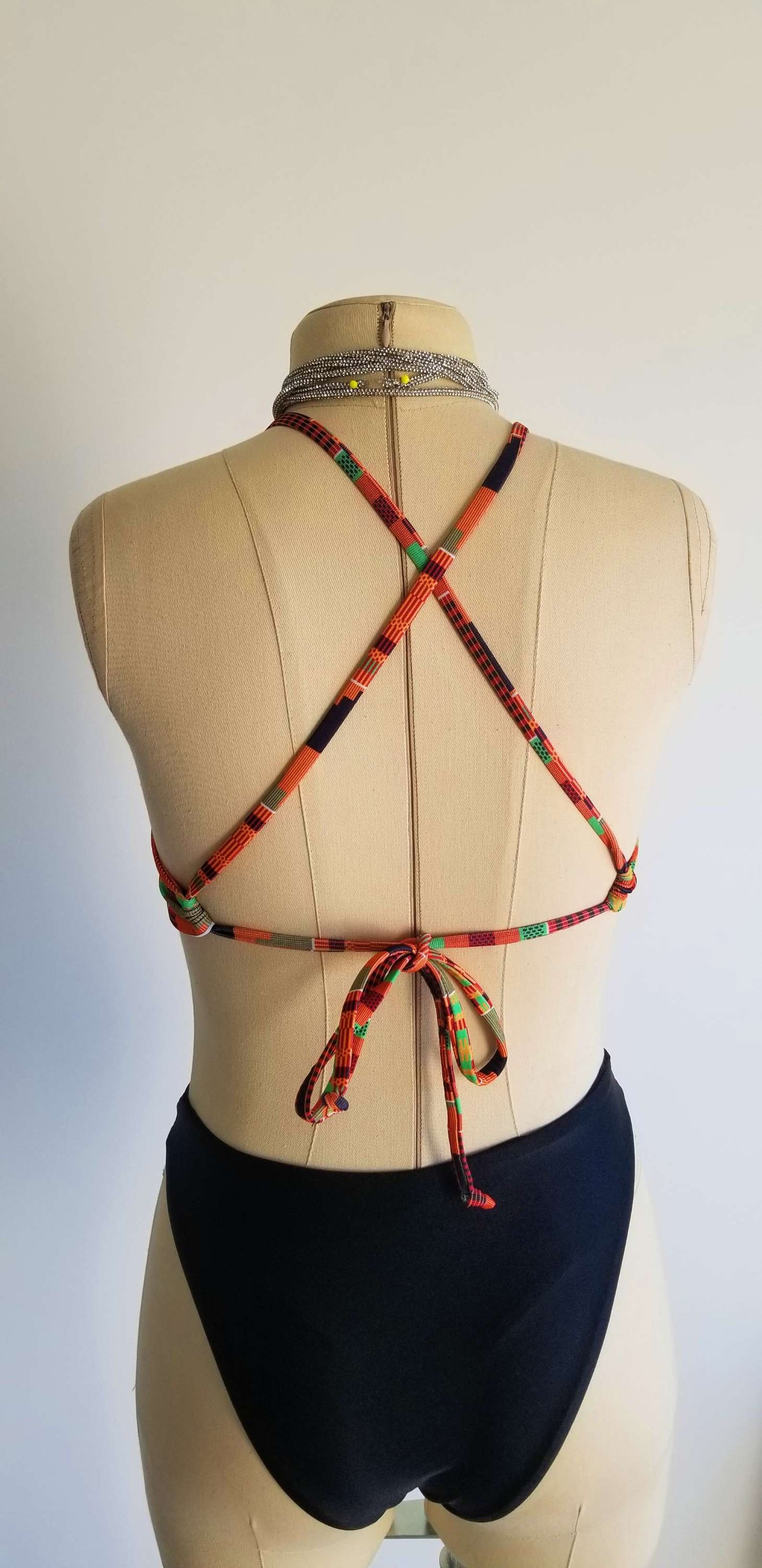 A styling collage of the multicolored African print Heritage Infinity top showing the back view with wrap-around ties and various front-styling options.