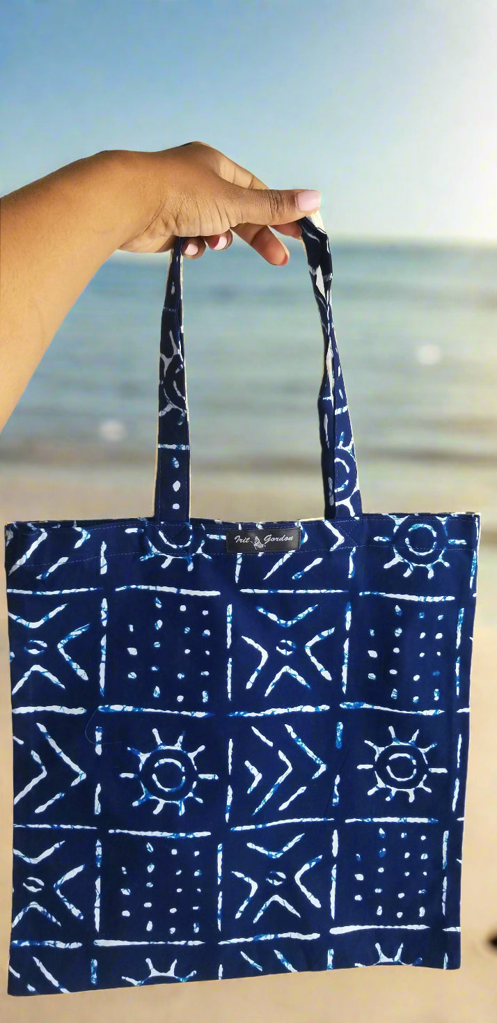 ​Handmade indigo blue and white mudcloth print tote bag by Scope and Flow, styled outdoors.

