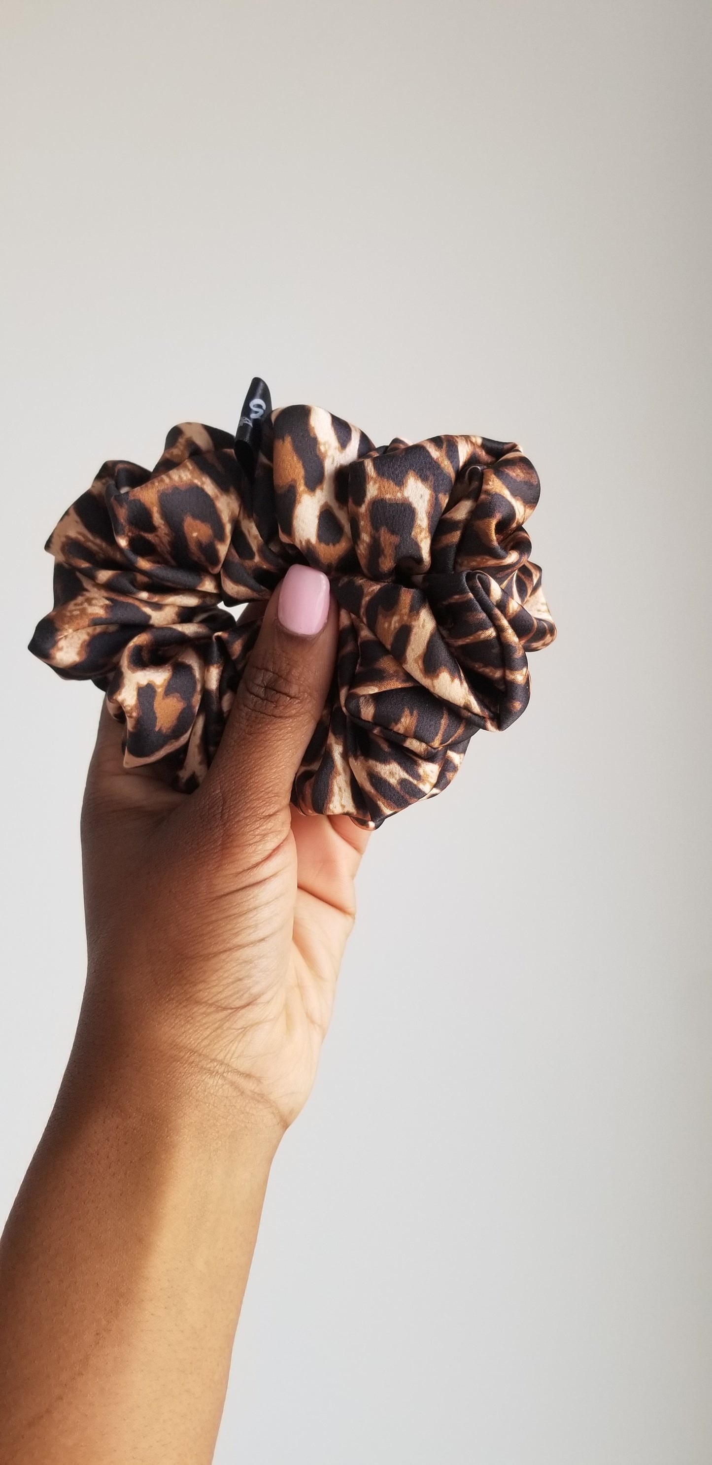 Handmade leopard print silk scrunchie by Scope and Flow, styled on a white marble vanity.