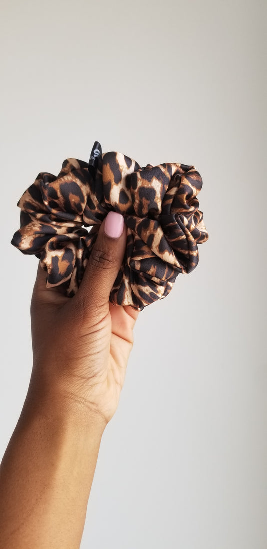 Handmade leopard print silk scrunchie by Scope and Flow, styled on a white marble vanity.