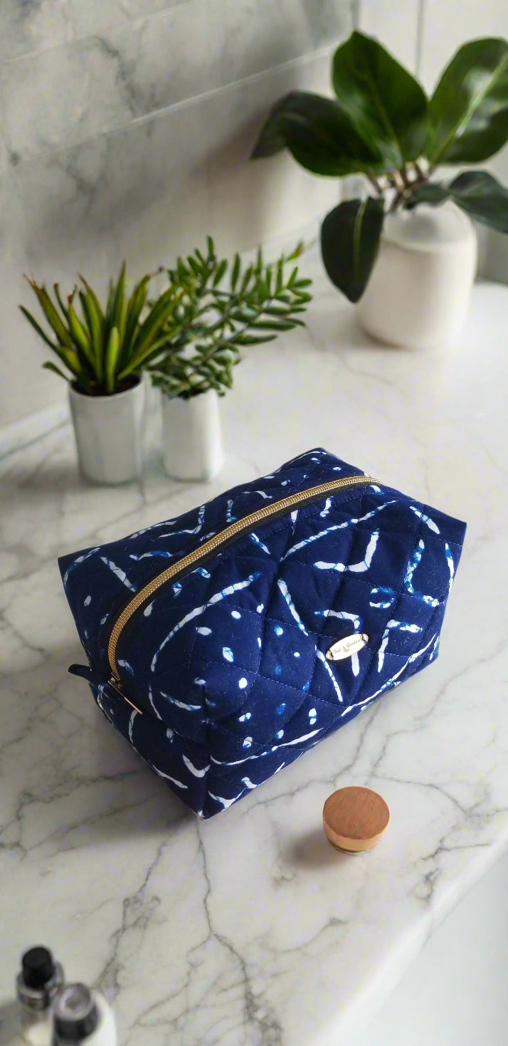 Side view of the handmade dark blue tribal makeup bag styled with gold bathroom accents.