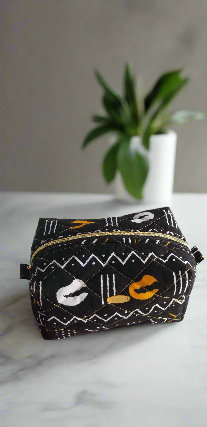 Close-up detail of the simplified black, white, and gold geometric pattern on the Odyssey Noir makeup bag.