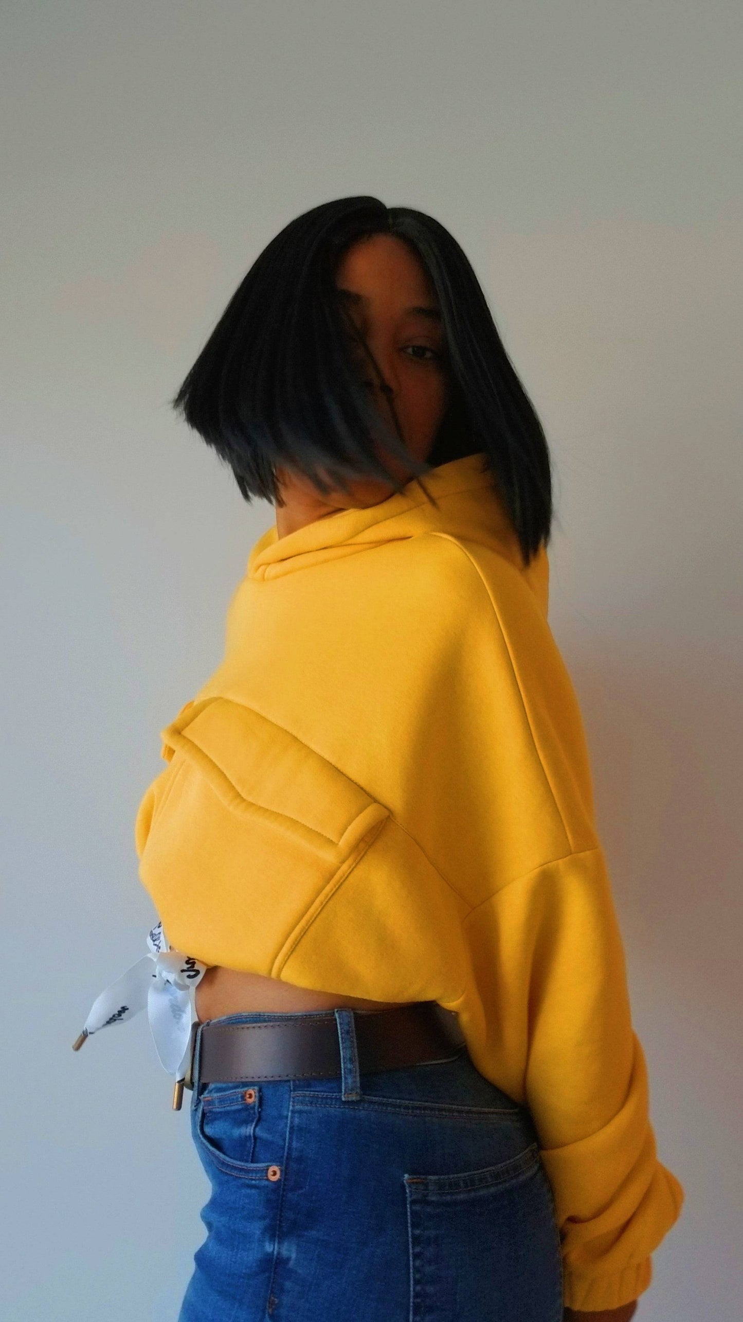 a woman wearing a yellow hoodie and jeans