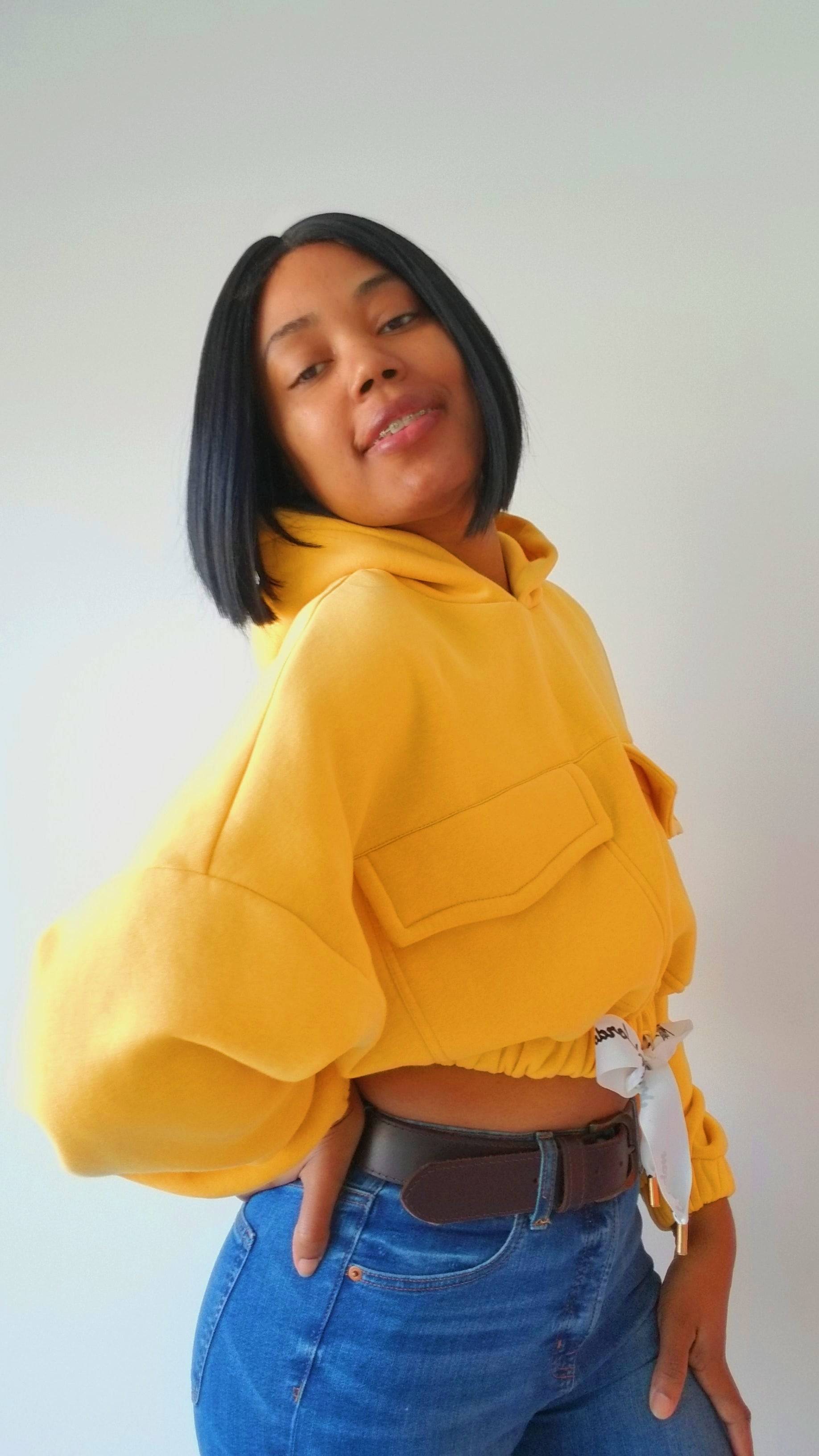 a woman in a yellow hoodie poses for a picture