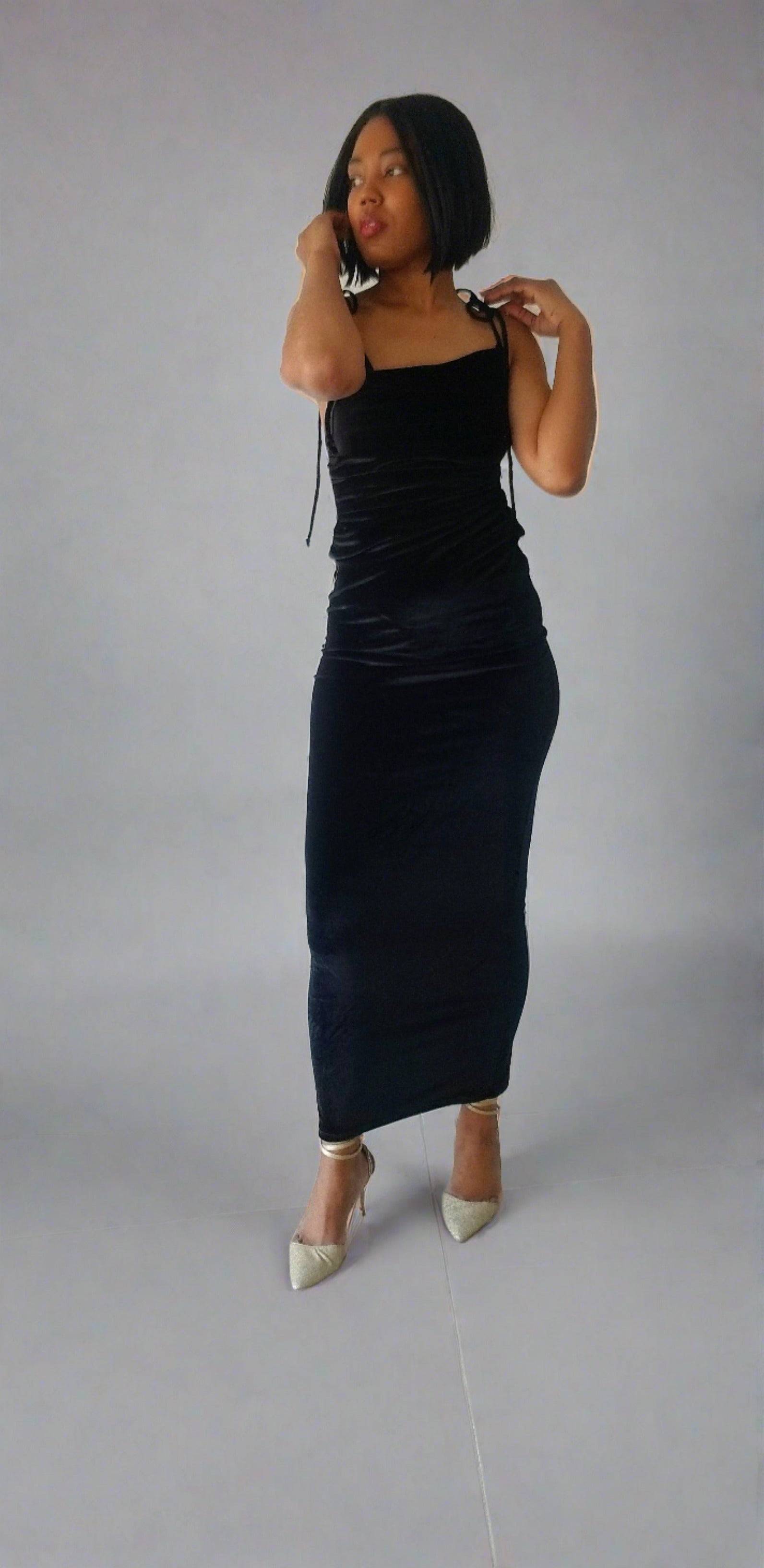 a woman in a black dress talking on a cell phone