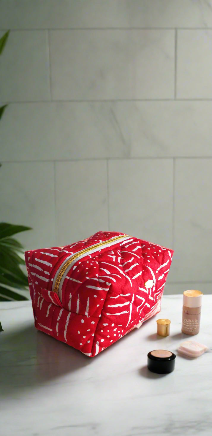 Front view of the Ruby Geometric red and white makeup bag by Scope and Flow on a luxury marble vanity.