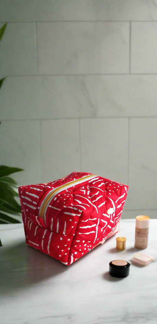Front view of the Ruby Geometric red and white makeup bag by Scope and Flow on a luxury marble vanity.