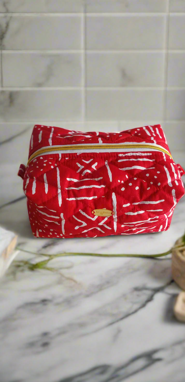 Side perspective of the handmade red and white Ruby makeup bag styled with gold bathroom fixtures.