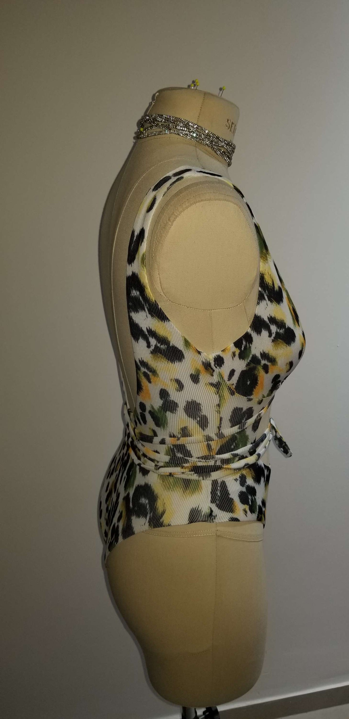 Close-up of the emerald leopard bodysuit showing the premium fabric texture and the signature Scope and Flow hangtag.