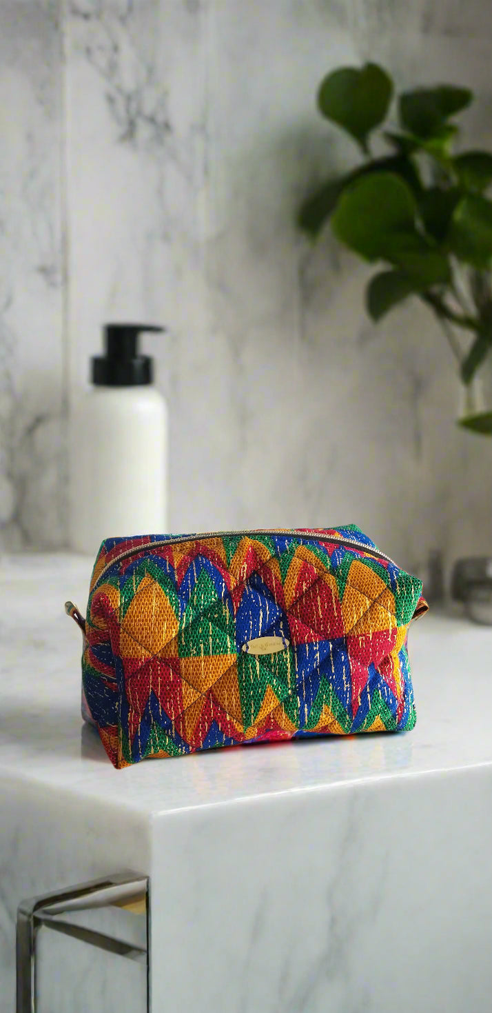 Front view of the multicolored red and blue Solaris tribal makeup bag by Scope and Flow on a marble vanity.