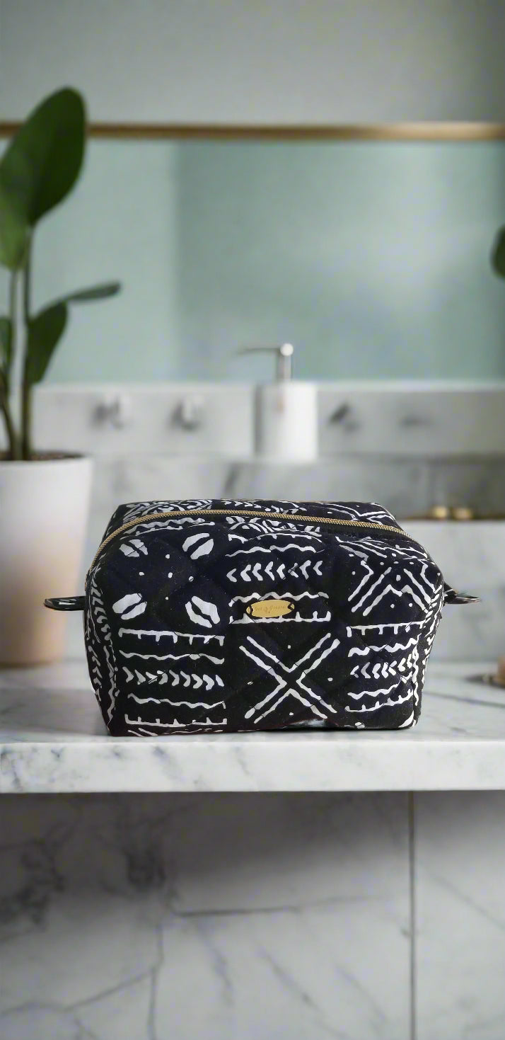 Front view of the Tribal Noir makeup bag by Scope and Flow, featuring black and white geometric patterns on a white marble counter.