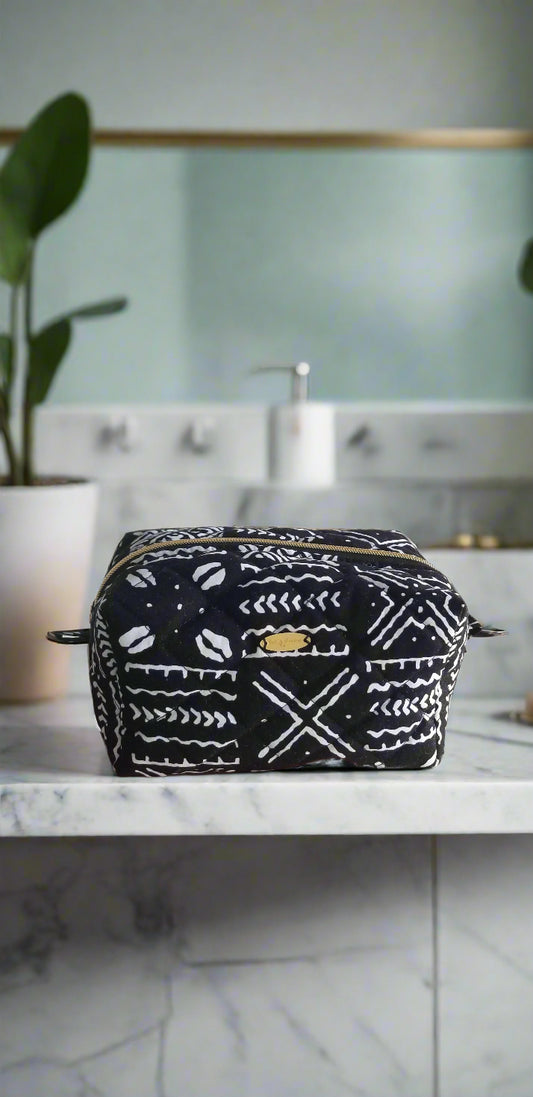 Front view of the Tribal Noir makeup bag by Scope and Flow, featuring black and white geometric patterns on a white marble counter.