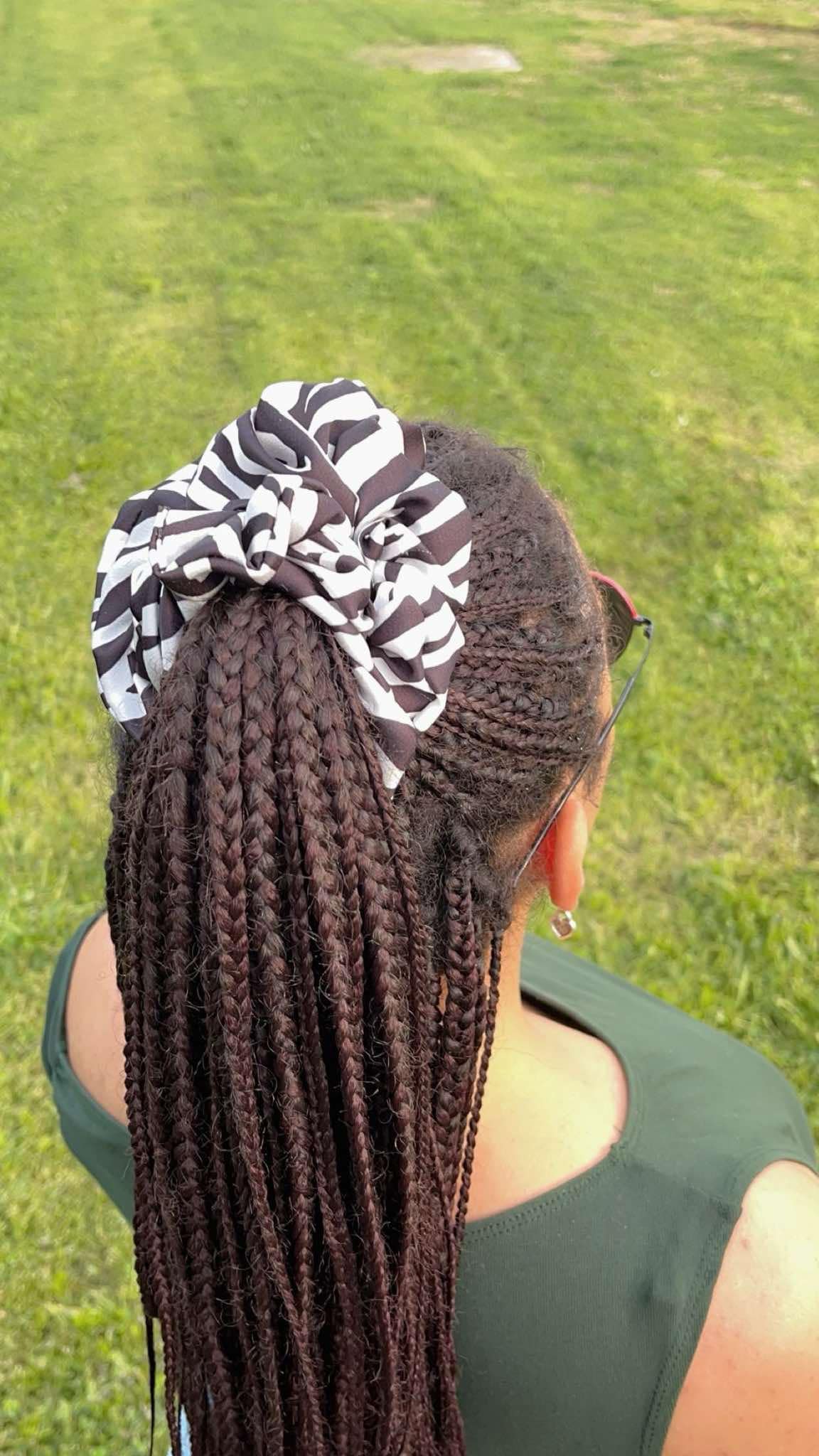 Close-up view of the high-contrast zebra pattern and soft silk fabric of the Scope and Flow hair tie.