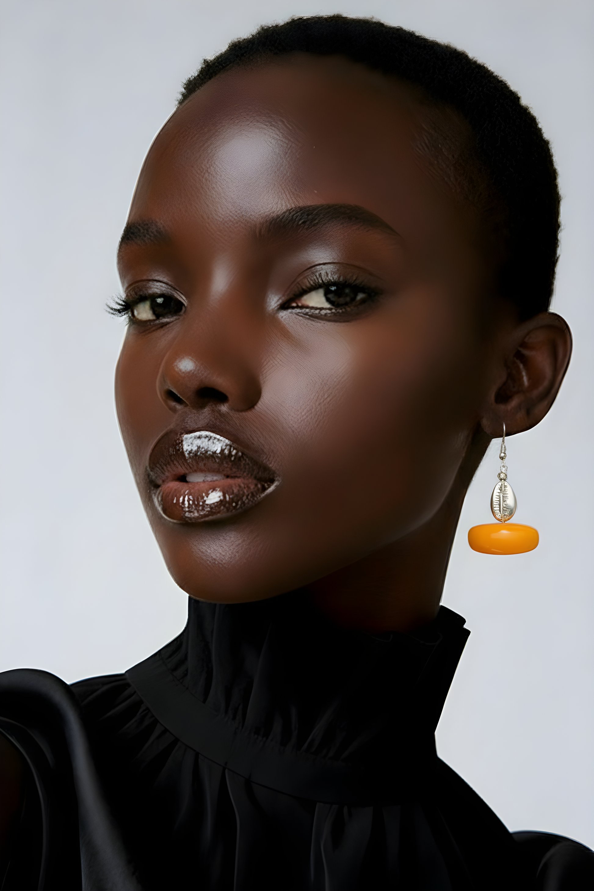 Model wearing Scope and Flow Zora earrings in Amber resin with a natural cowrie shell accent.