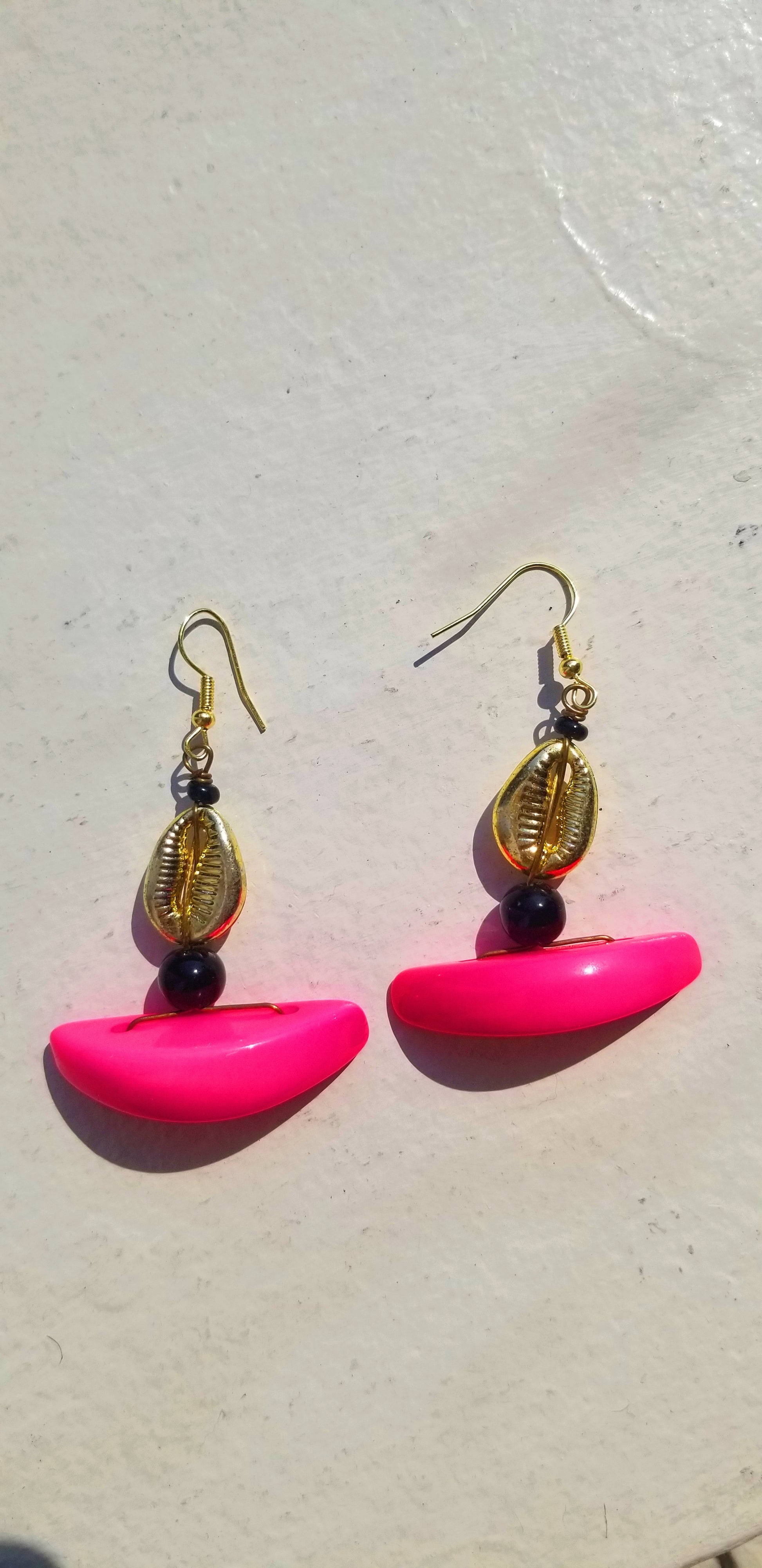 Vibrant hot pink resin drop earrings with artisanal cowrie shell and black glass bead.