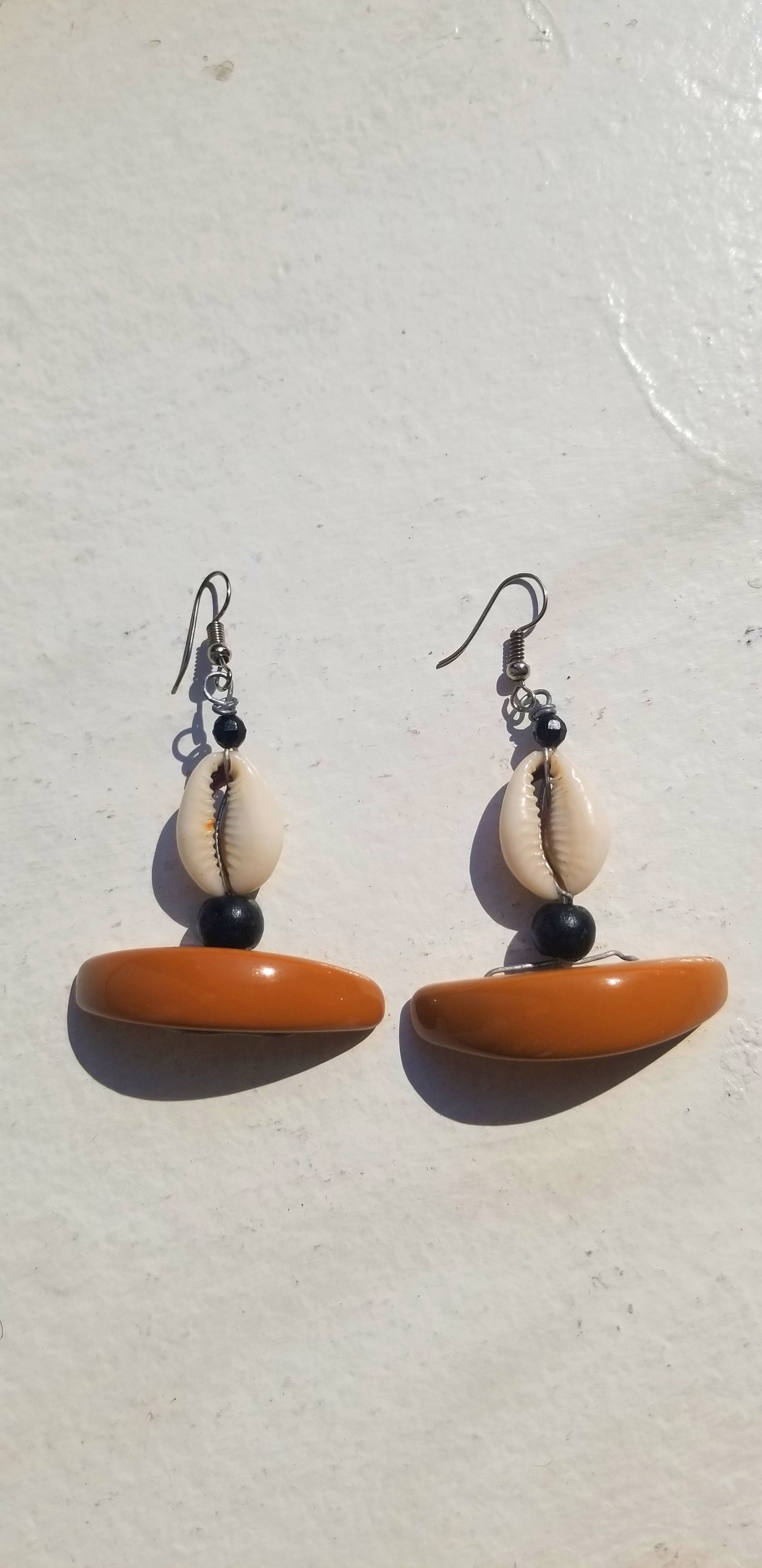Rich earth-toned brown resin earrings featuring natural cowrie shell textures.